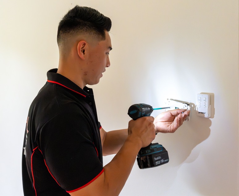 Electrician installing wall-mounted device.