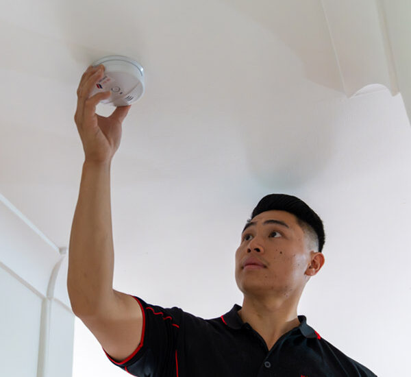 electrician installing a smoke alarm on the ceiling